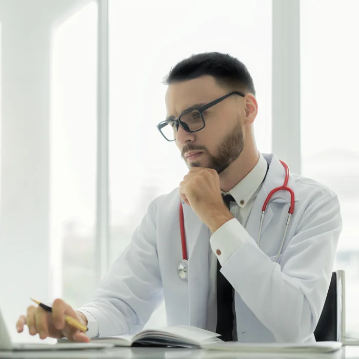 Physician at his desk reviewing his practice website on a laptop